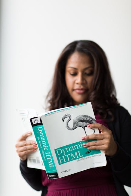 There is no gardening or outdoor scene in this image. It features a woman with dark brown hair reading a book titled 'Dynamic HTML' with an illustration of a flamingo on the cover. She is dressed in a